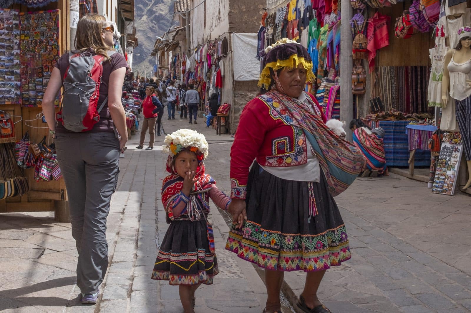 Women in traditional dress walking through the market street at Pisac