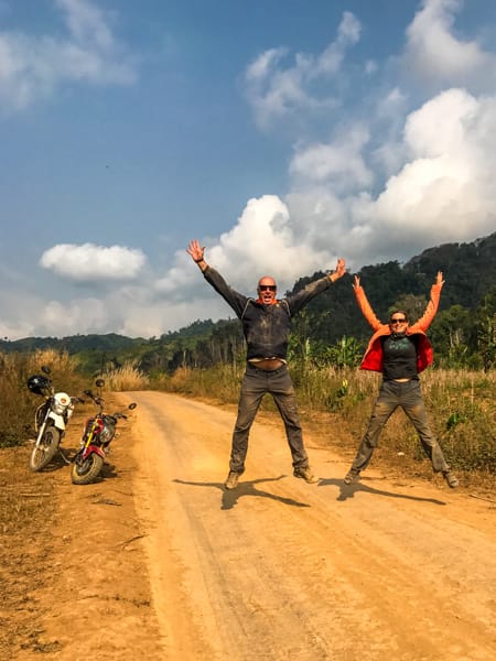 Steve and Julie jumping for joy on a dirt road in Laos